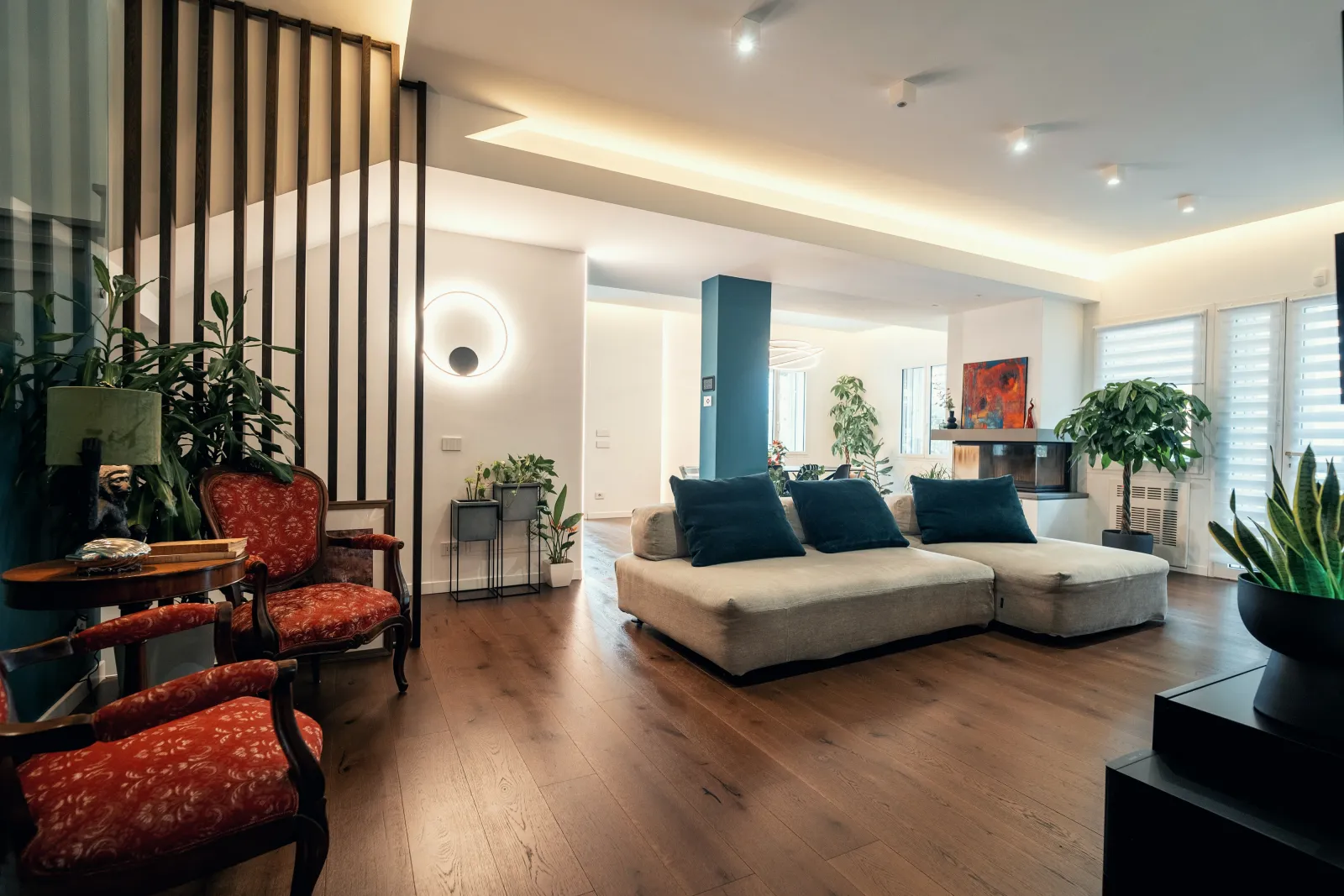 Soggiorno con parquet in rovere, divano ad angolo e parete divisoria in legno, dopo la ristrutturazione