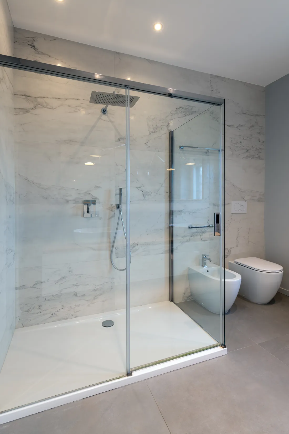 Bagno rivestito in marmo bianco con doccia walk-in e soffione a pioggia