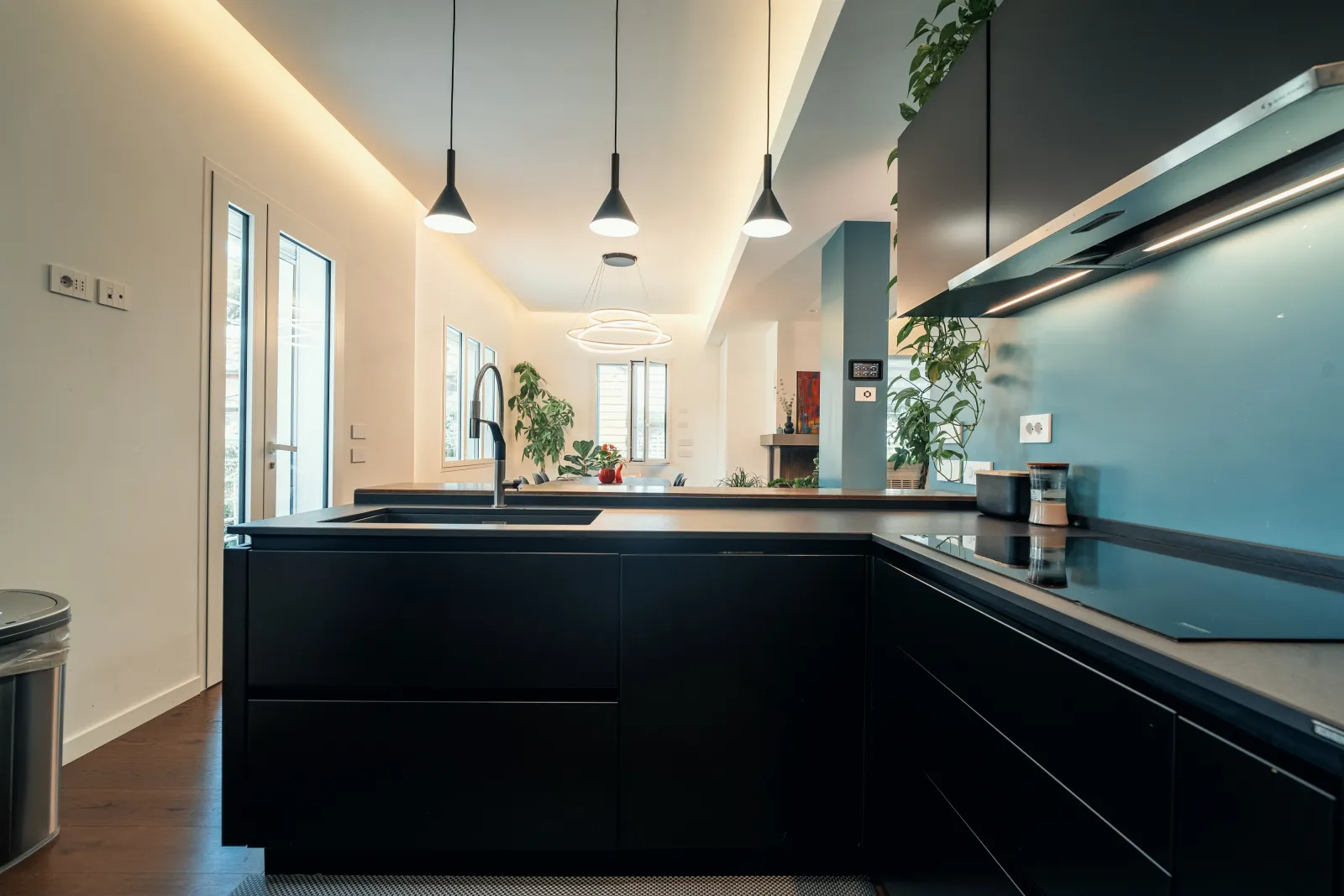 Cucina ad angolo con ante nere opache, piano in pietra e schienale azzurro